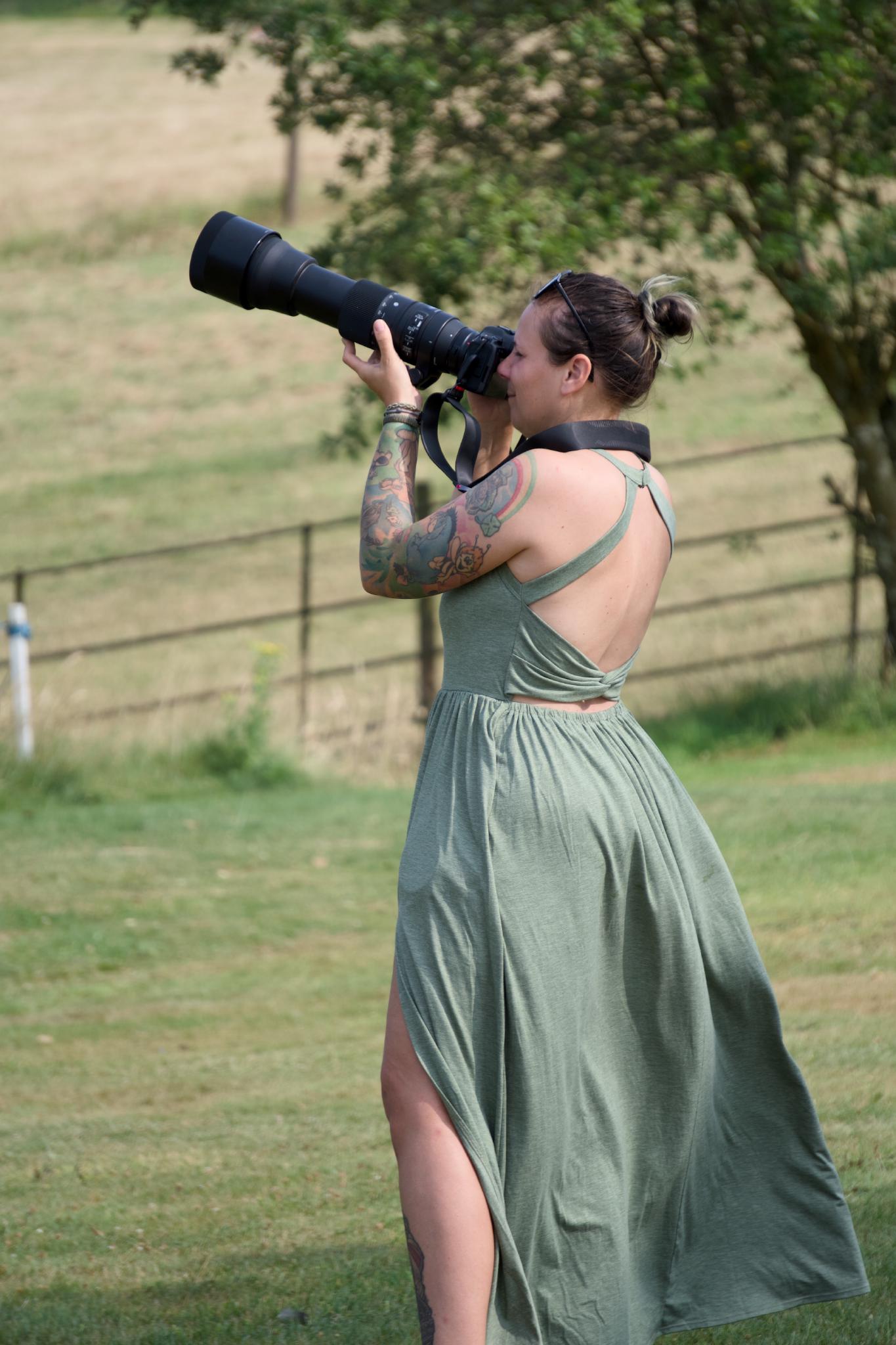 Nadine in a green dress aiming a long telephoto lens