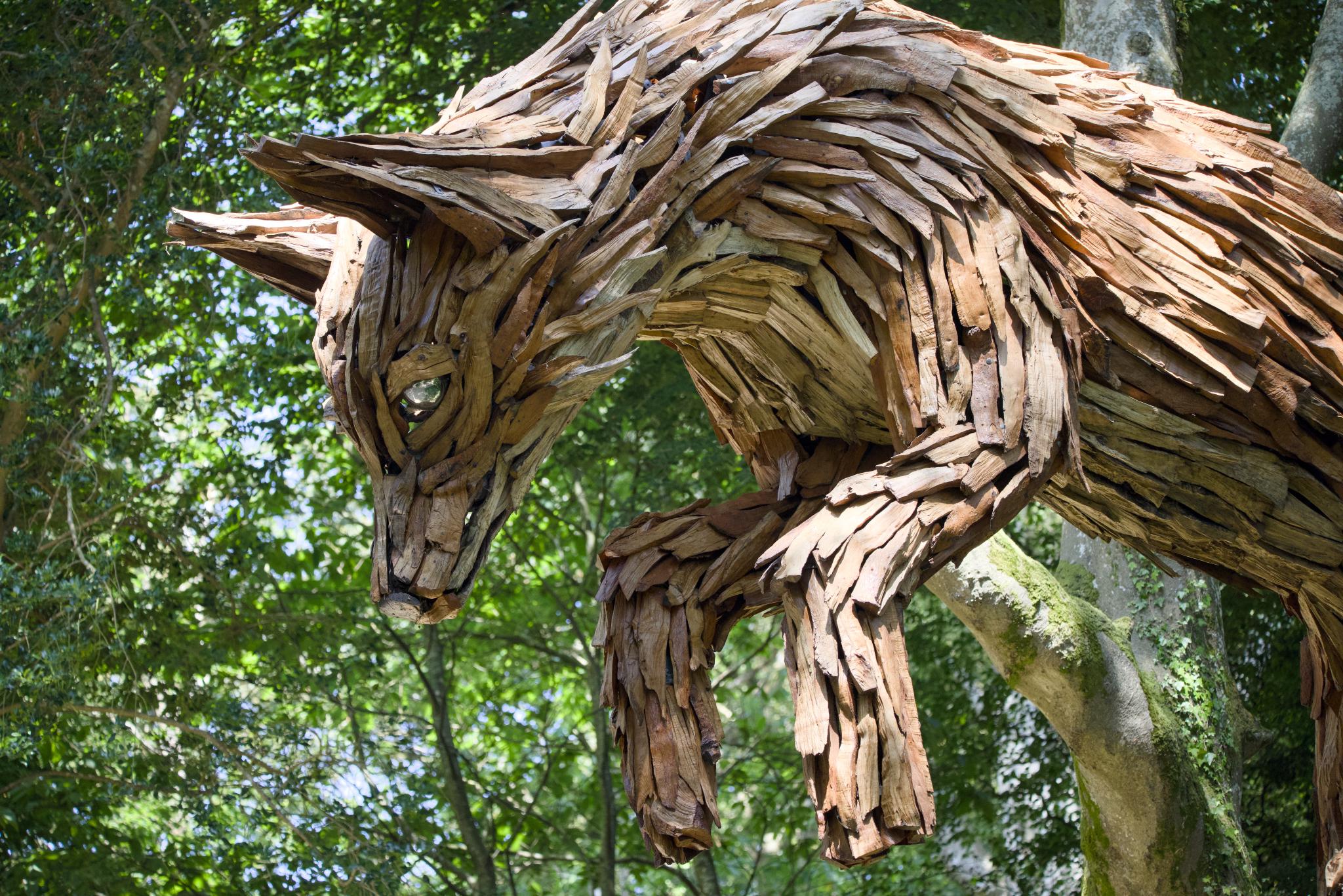 Wooden fox sculpture leaping off a tree trunk