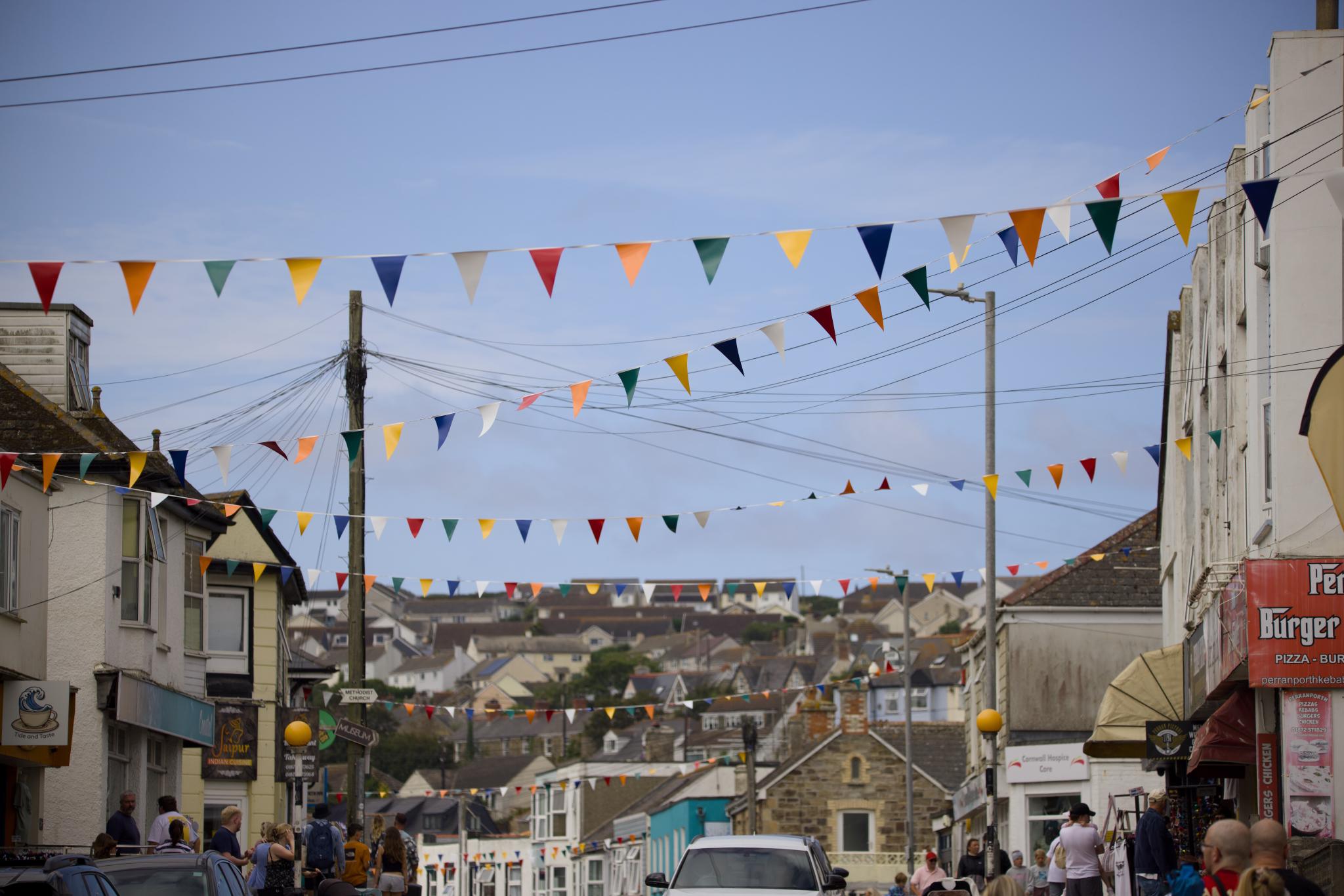 Bunting strung across the main street of Perranporth, houses on the hillside behind