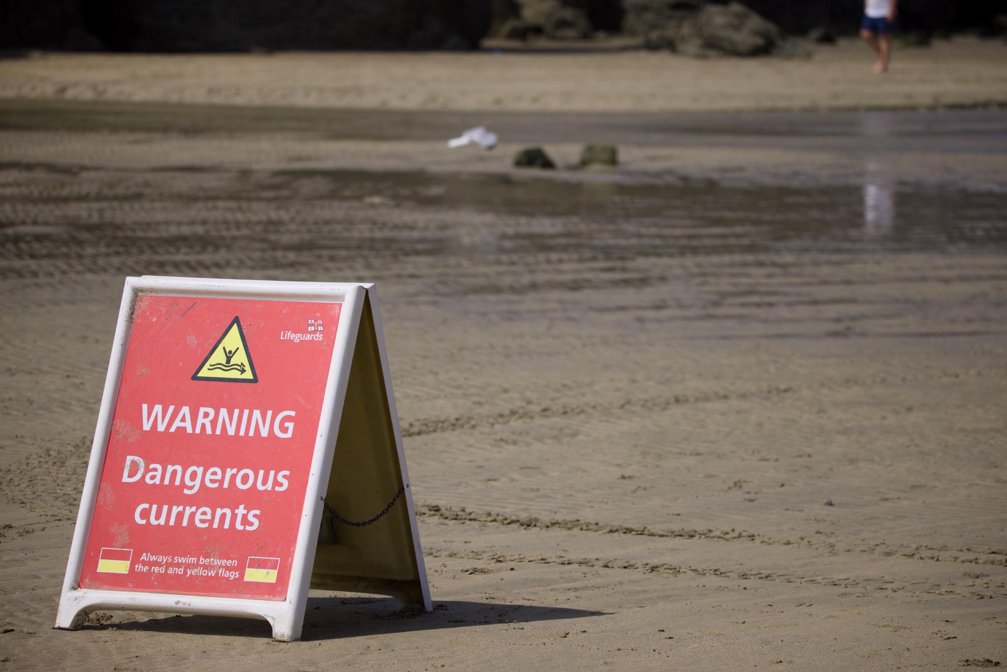 Lifeguard sign on the beach warning of dangerous currents