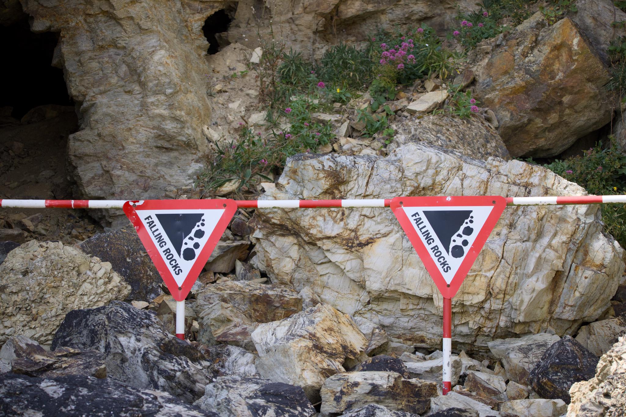 Falling rocks signs on a barrier in front of a rock fall