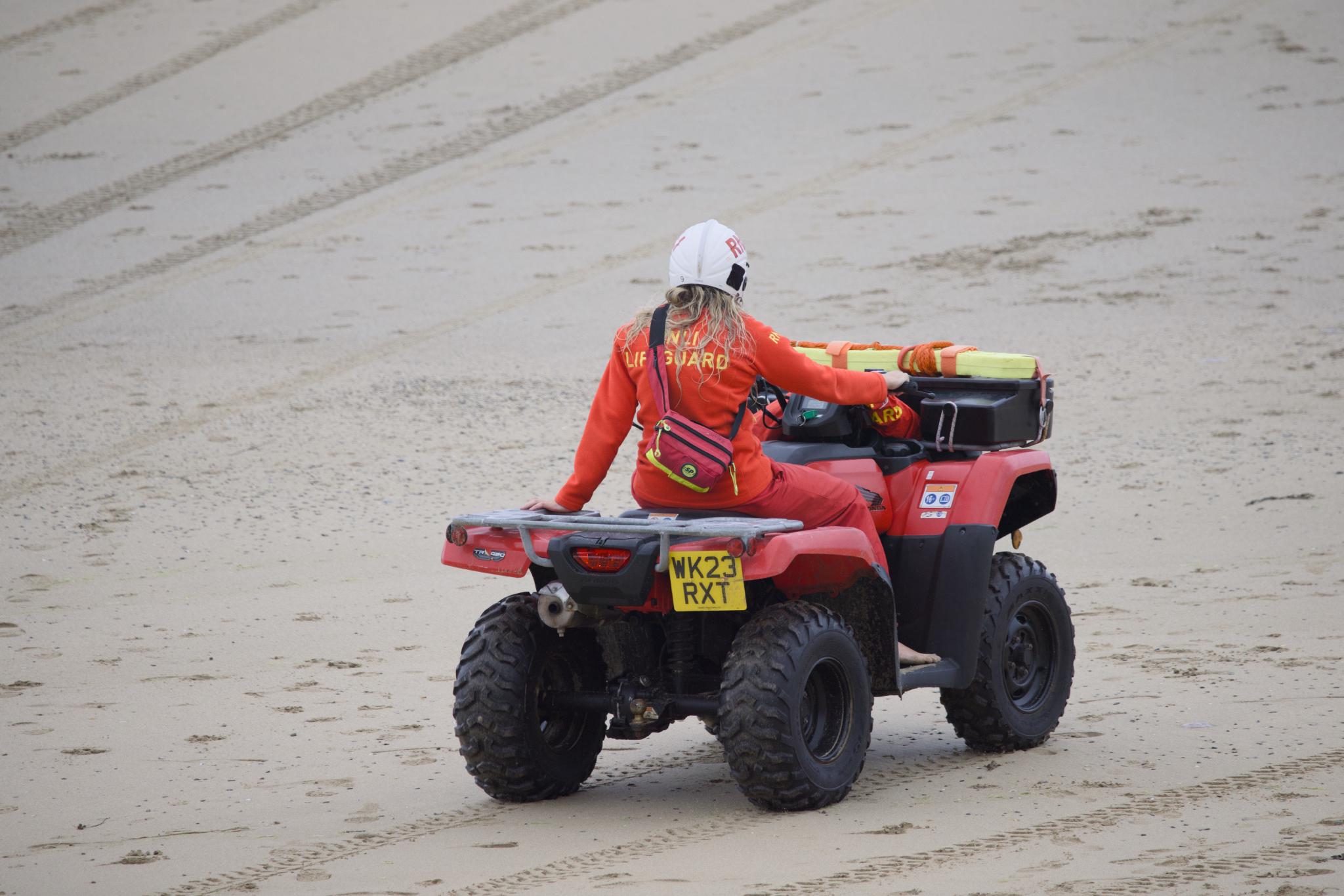 RNLI lifeguard riding a quad bike across the beach