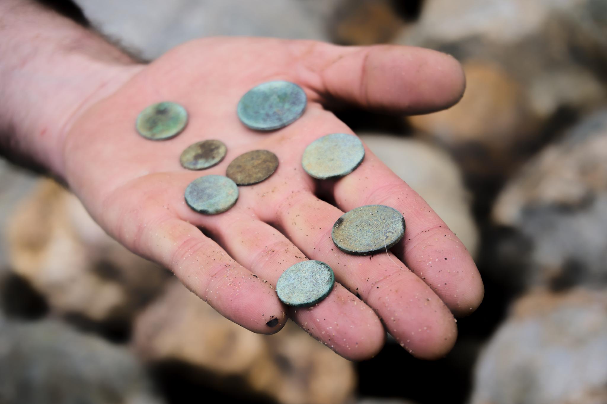 A local metal detectorist showing a hand full of corroded coins