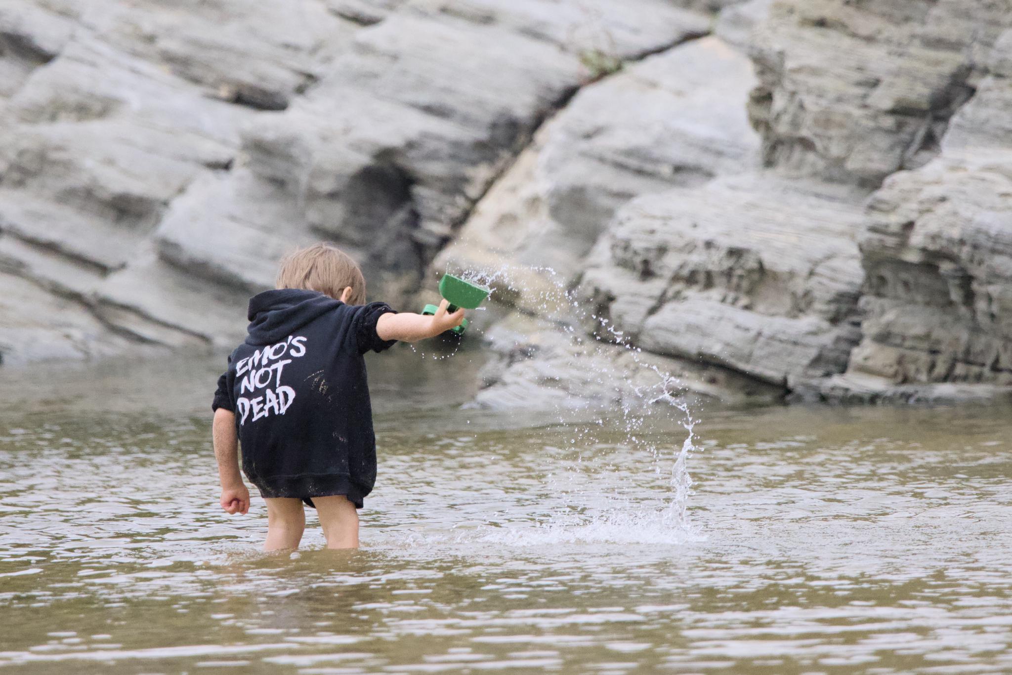 Boy in an Emo's Not Dead hoodie splashing water in front of the rocks