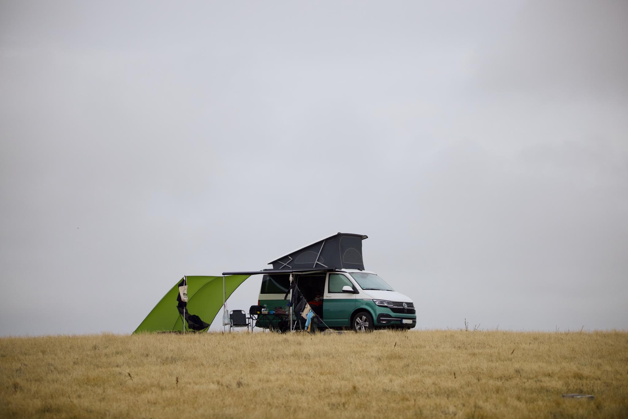 The California with the roof up and a green windbreak on the cliff-top field