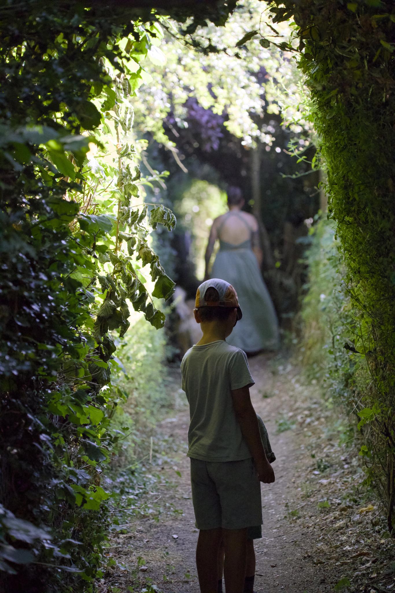 Tilian in the foreground, Nadine and Kellin ahead in a green hedge tunnel