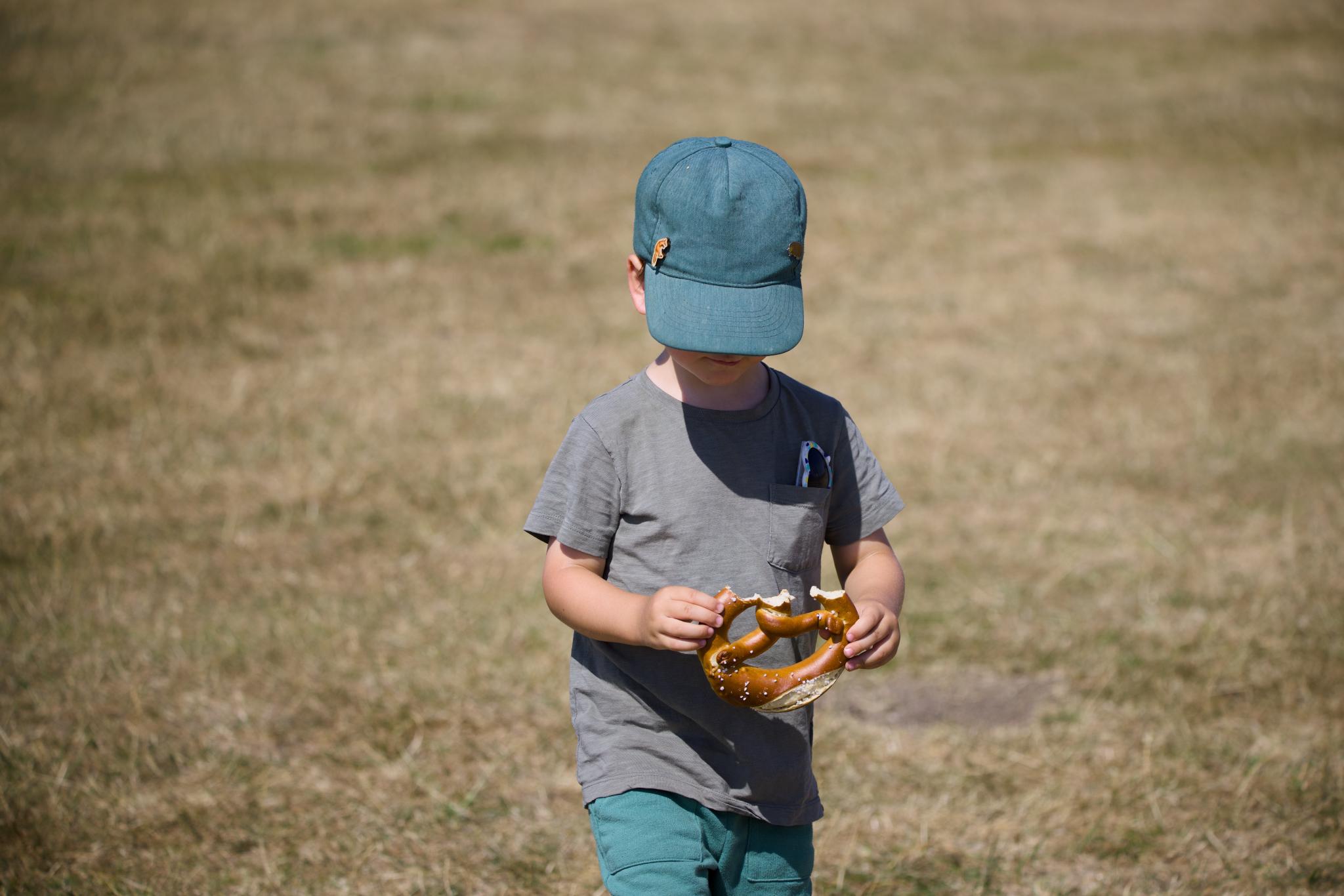 Kellin with a green cap eating a large pretzel
