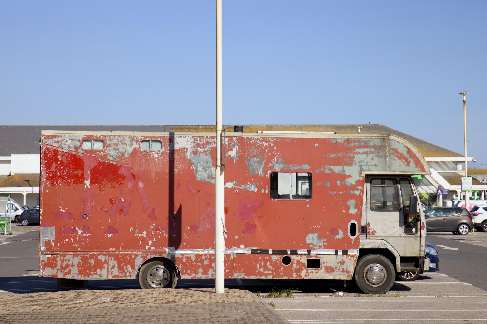 Weathered red horsebox camper in a supermarket car park