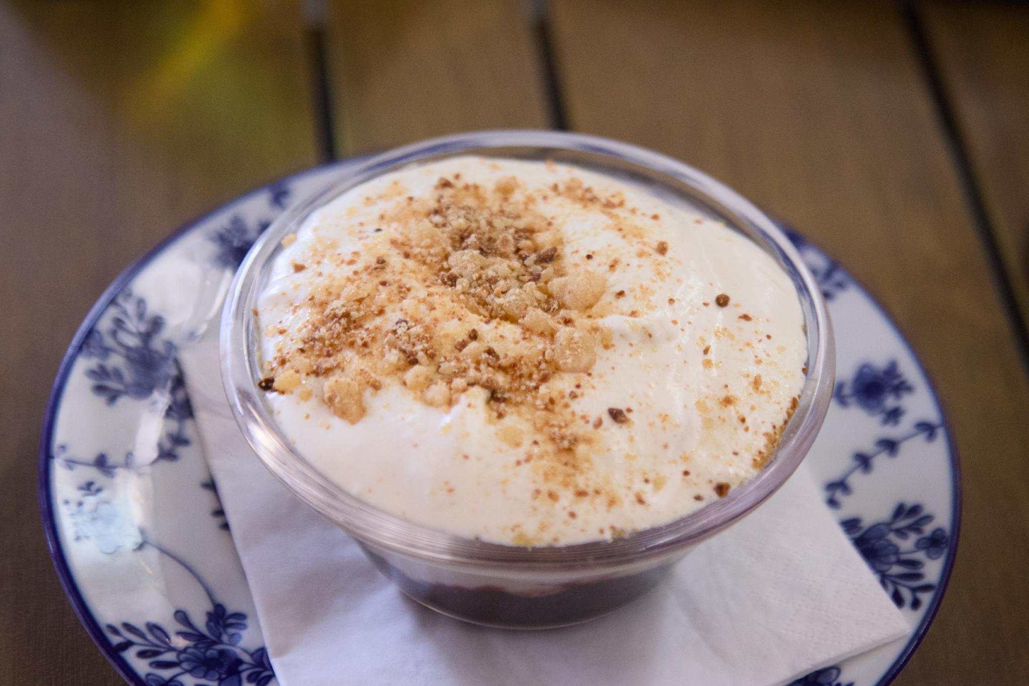 Glass bowl of dessert topped with whipped cream and crumble