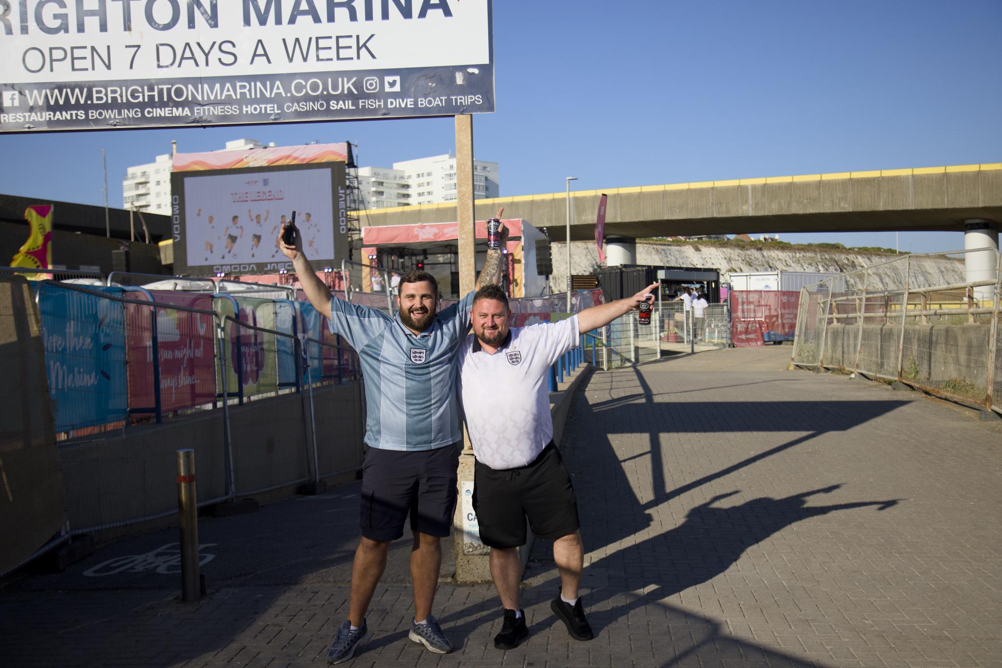 Two England fans posing under the Brighton Marina sign