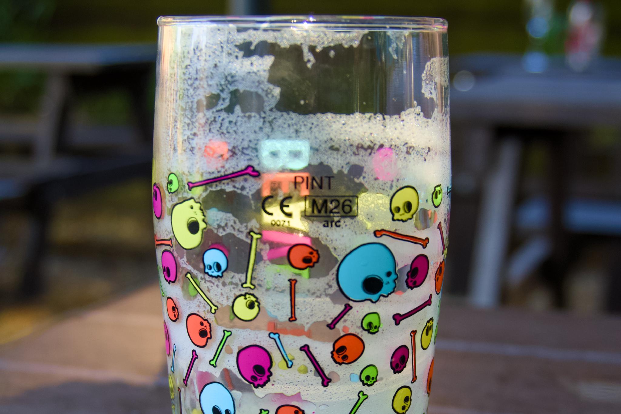Empty pint glass printed with colorful skulls and bones