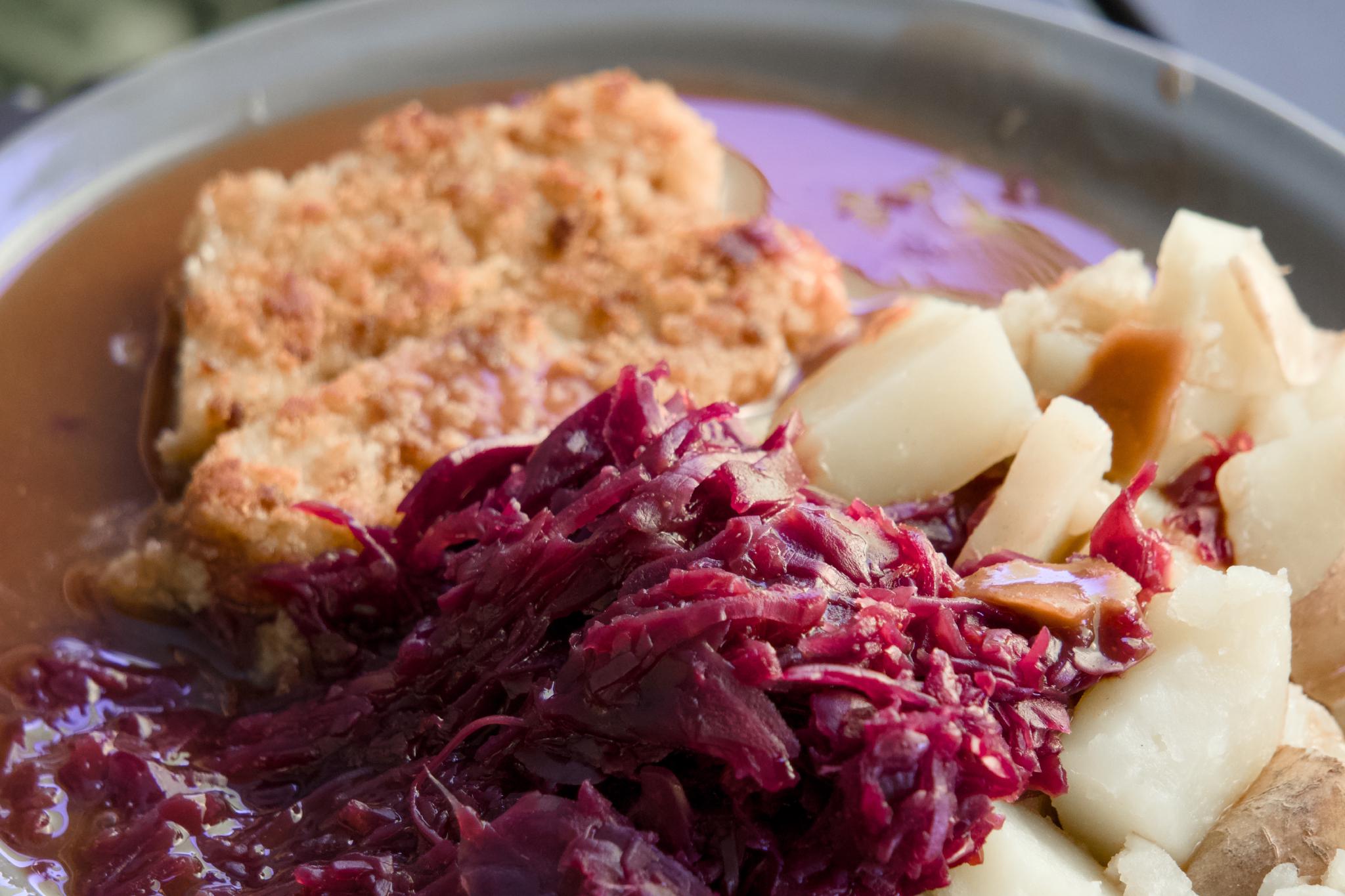 Plate with a breaded cutlet, red cabbage, potatoes and gravy