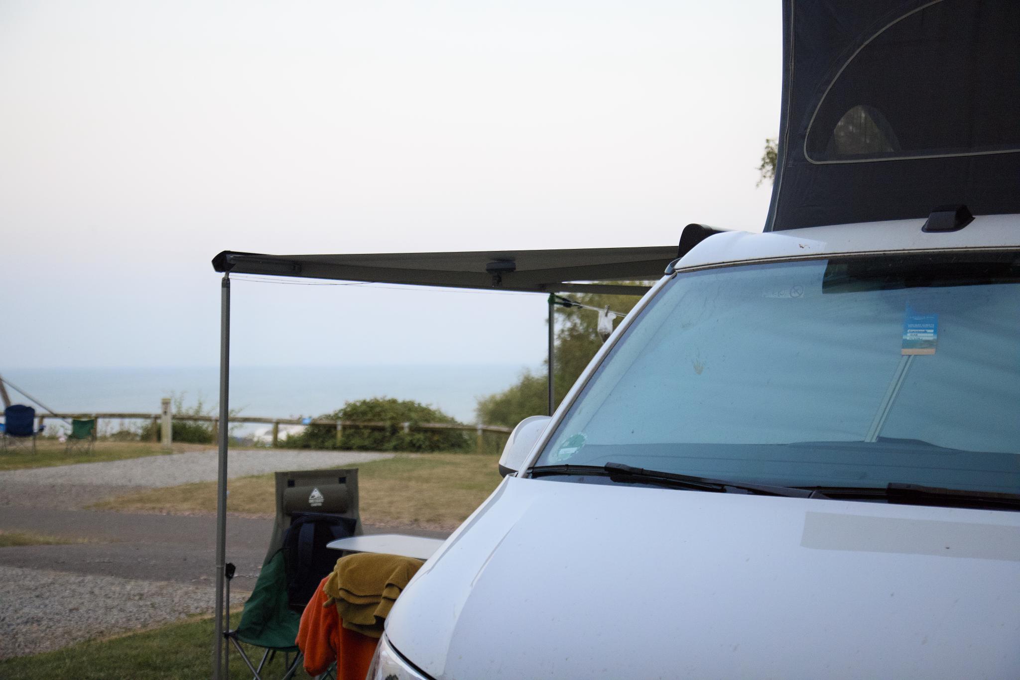 California with the roof up and the awning out, the sea in the background