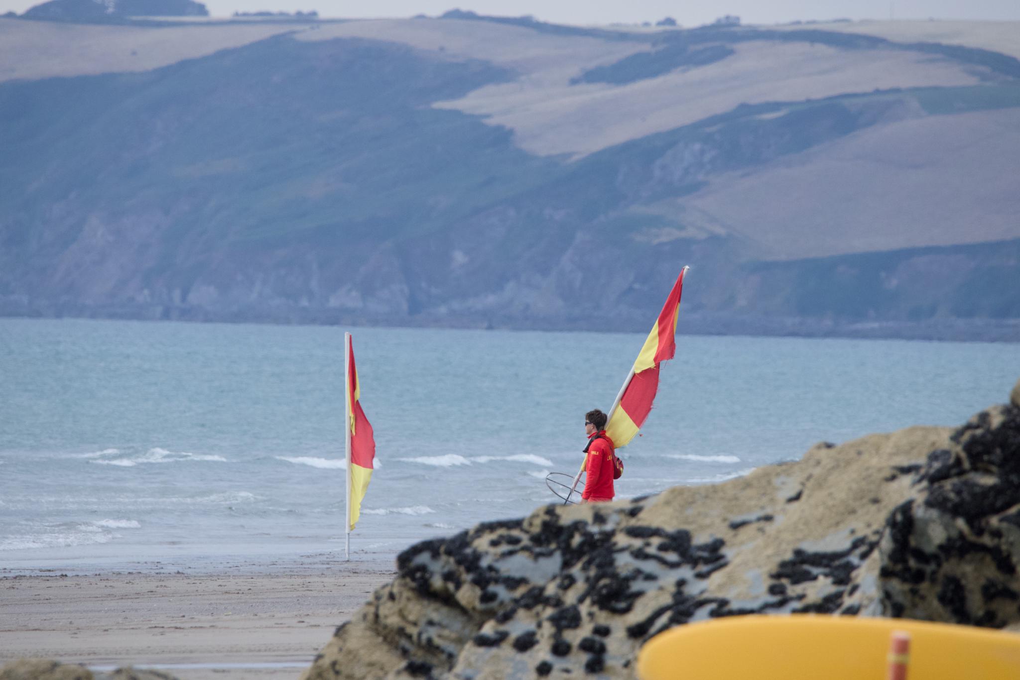 Lifeguard carrying the red and yellow flags off the beach