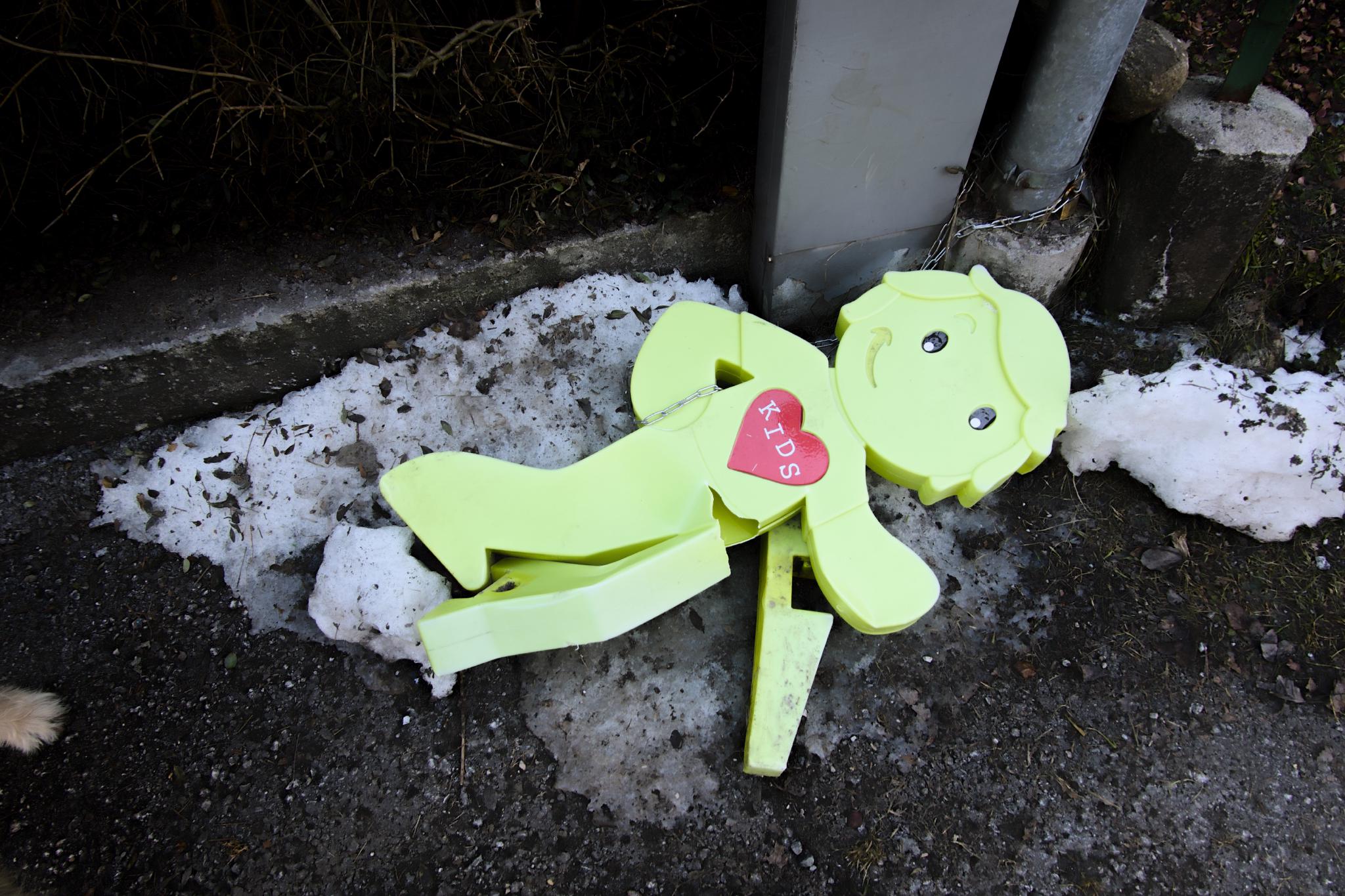 Broken sign warning of children in a snowy area