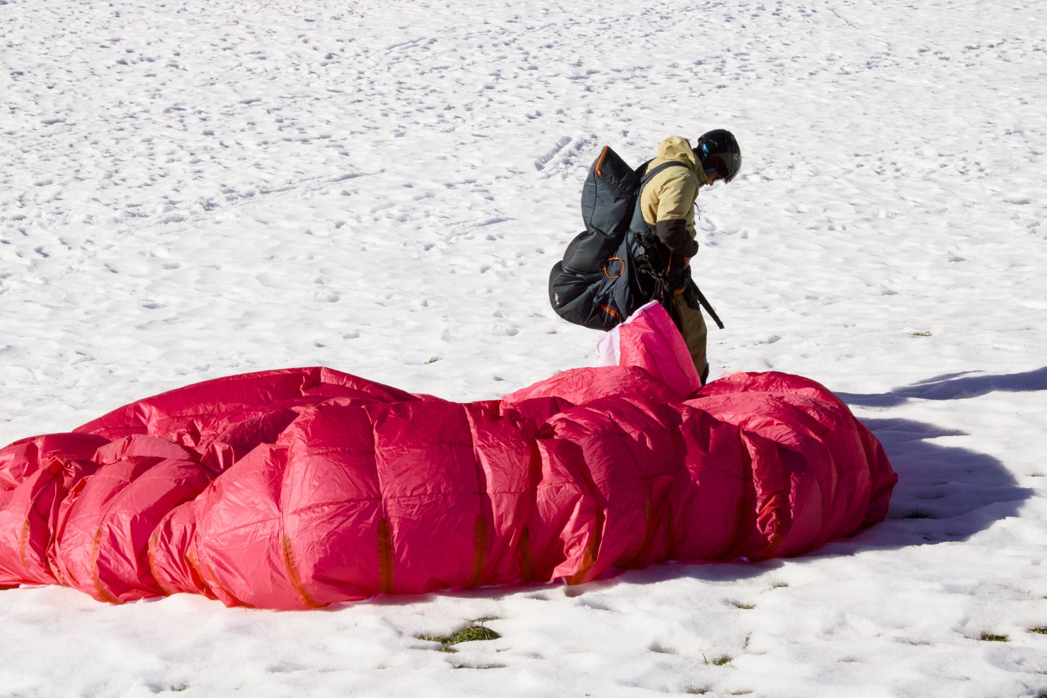 Tandem paraglider touching down in the snow