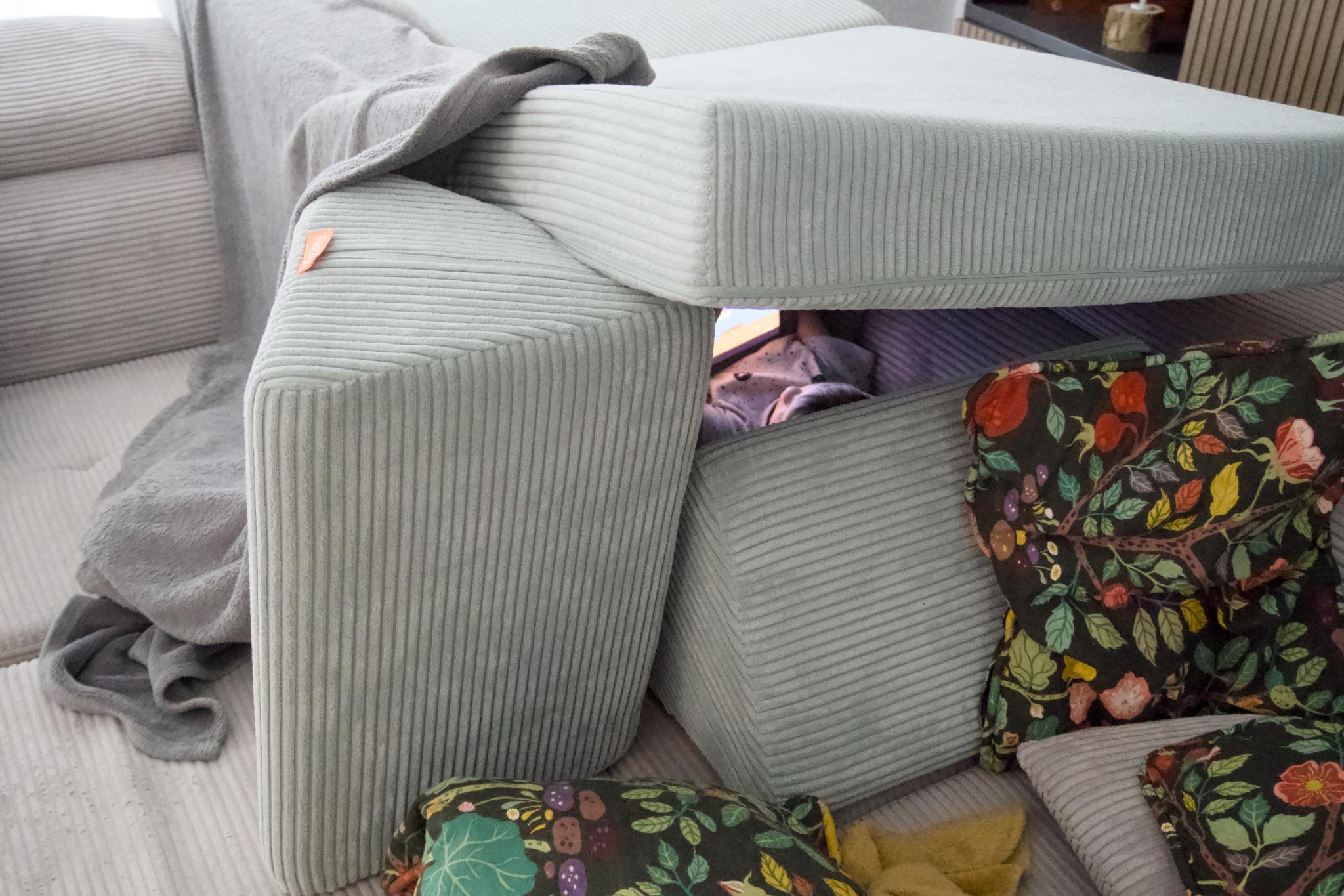 Pillow fort built from couch cushions and floral pillows