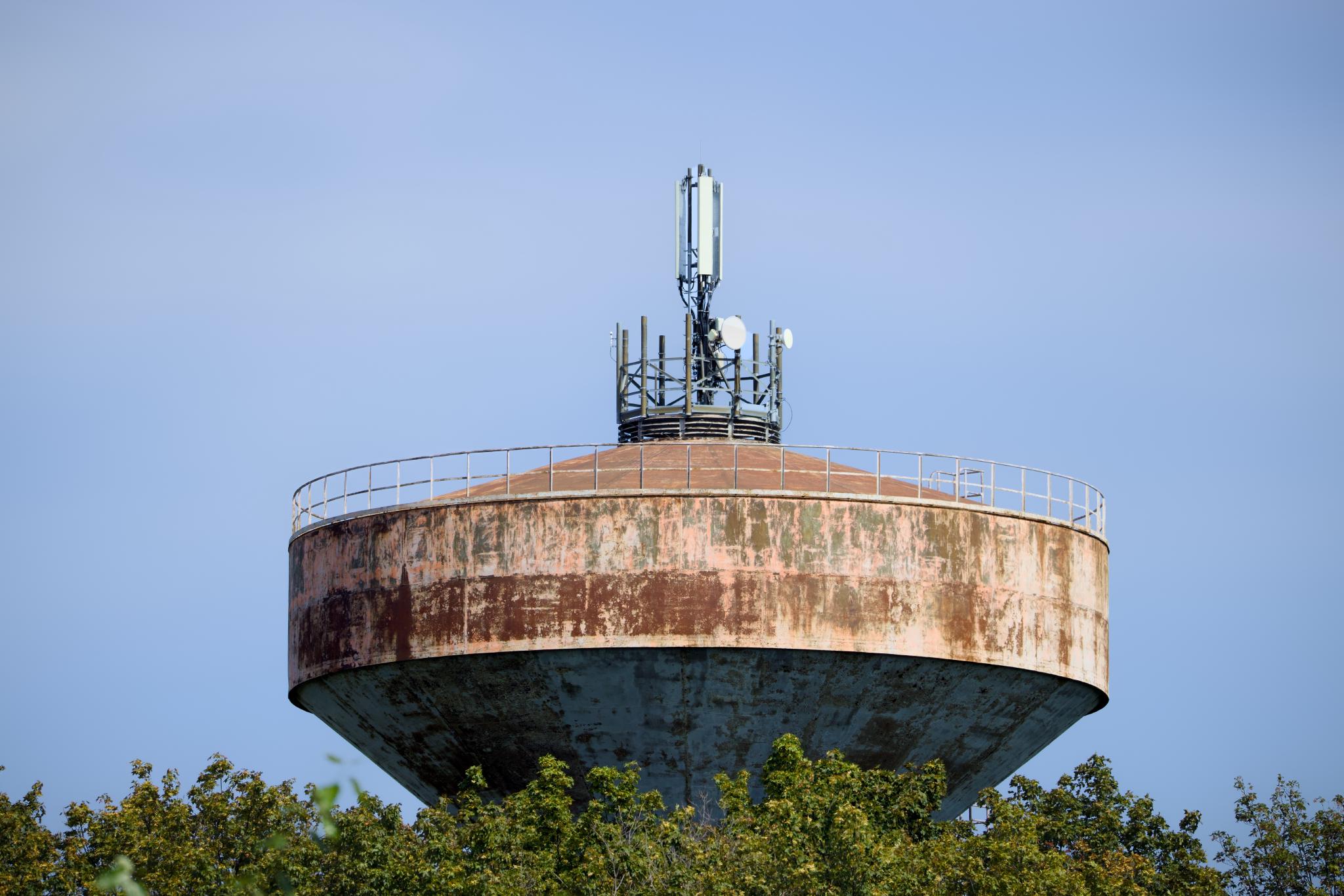 Weathered concrete water tower with mobile antennas on top